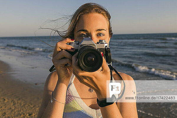 Woman holding camera near sea at beach
