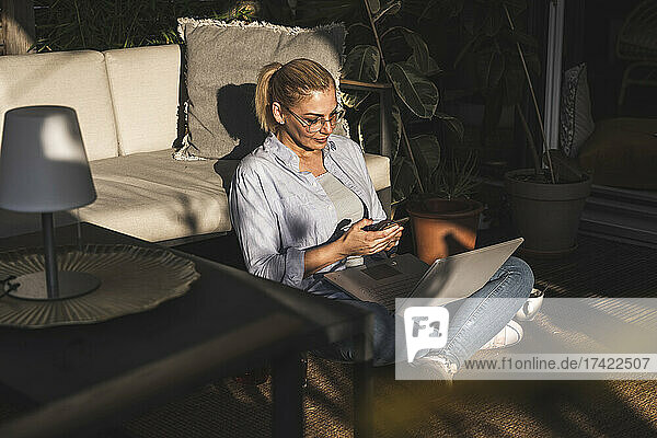 Female freelancer using mobile phone while working on terrace