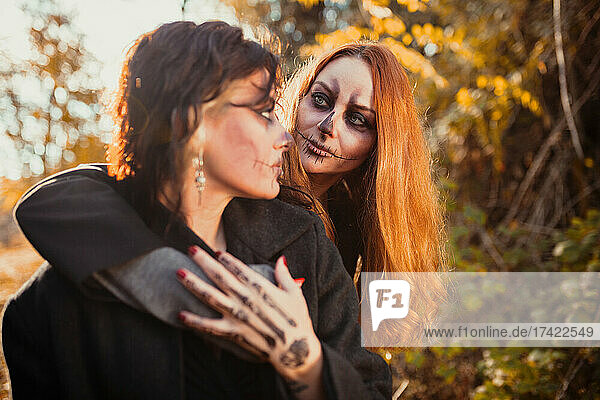 Frau mit Halloween-Make-up schaut Freundin im Wald an