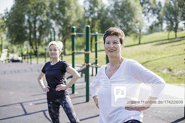 Women with hand on hip exercising at park