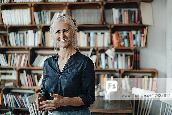 Smiling mature businesswoman with gray hair standing in cafe