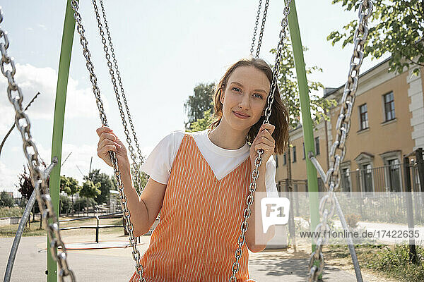 Smiling woman sitting on swing at park