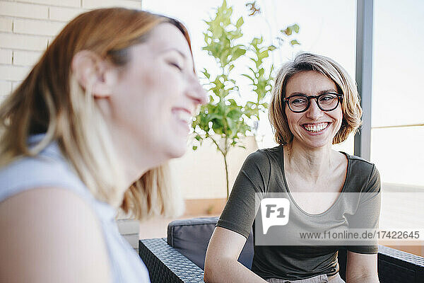 Smiling businesswoman looking at colleague while sitting at rooftop