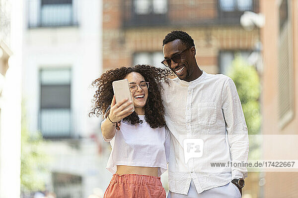 Happy man and woman taking selfie through smart phone