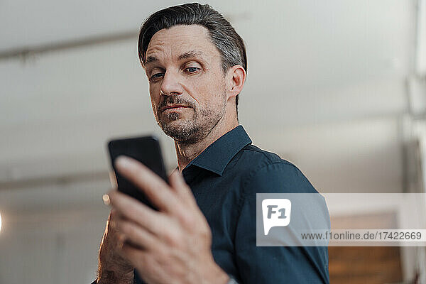 Mature man using smart phone in office