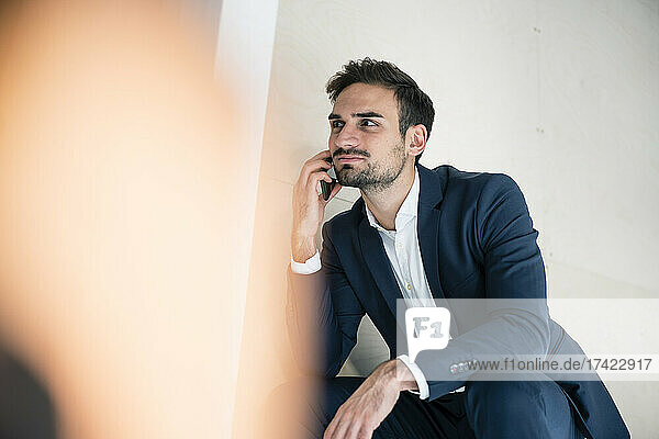 Handsome male professional talking on smart phone while working in office