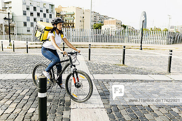 Weibliche Zustellerin fährt Fahrrad auf der Straße in der Stadt