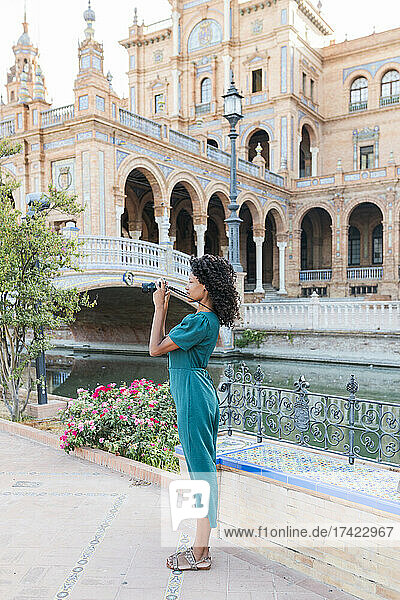 Young female tourist photographing through camera at Plaza De Espana  Seville  Spain