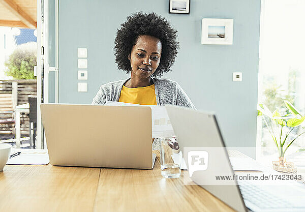 Afro businesswoman reading document at home office