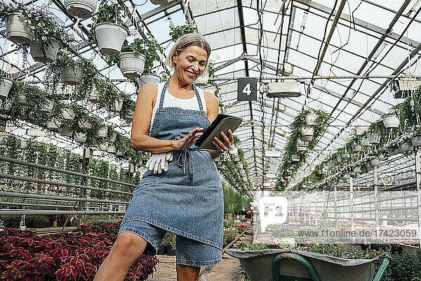 Smiling female agriculture worker using digital tablet at plant nursery