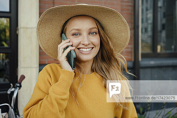 Schöne blonde Frau mit Hut  die auf dem Smartphone spricht