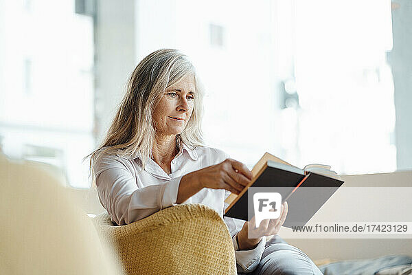 Mature woman reading book while sitting in cafe