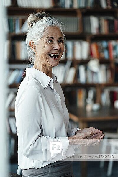 Cheerful woman with gray hair standing in cafe