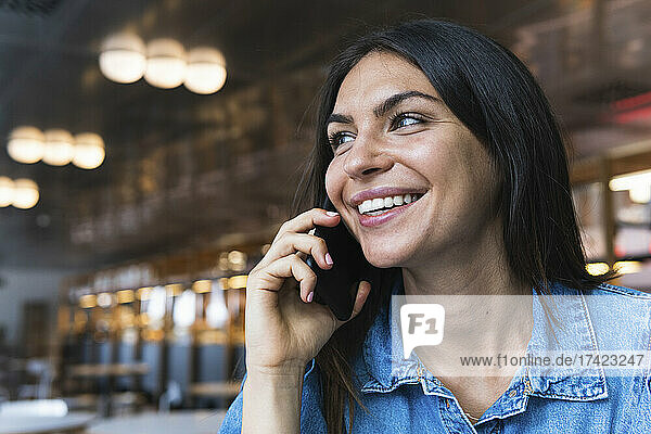 Beautiful female freelancer talking on mobile phone at cafe
