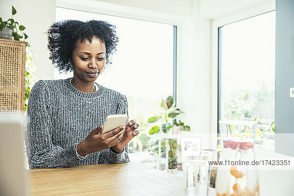 Female freelancer using smart phone at home office