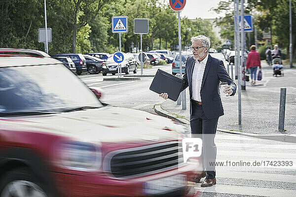 Shocked senior male professional crossing by speeding car