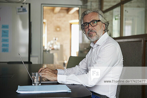 Male professional wearing eyeglasses working on laptop in office