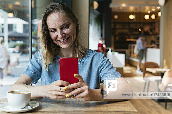 Female freelancer using smart phone while sitting at coffee shop