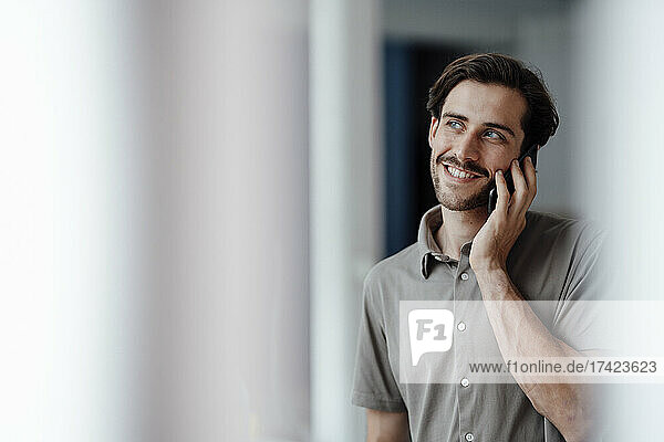 Smiling man talking on mobile phone at home