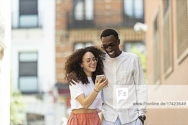 Man with arm around woman looking at smart phone