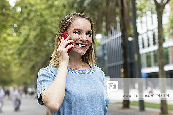 Glückliche blonde Geschäftsfrau  die am Smartphone spricht