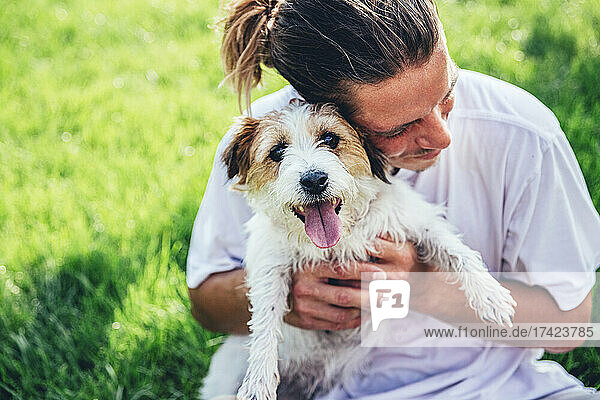 Mid adult man embracing dog in lawn