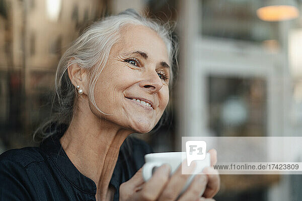 Smiling woman holding coffee cup in cafe
