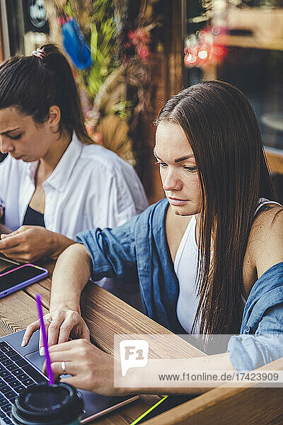 Young female freelancers telecommuting at sidewalk cafe