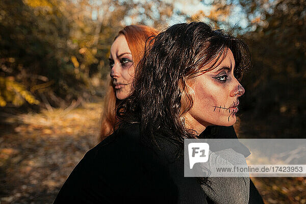 Friends with spooky make-up in forest during Halloween
