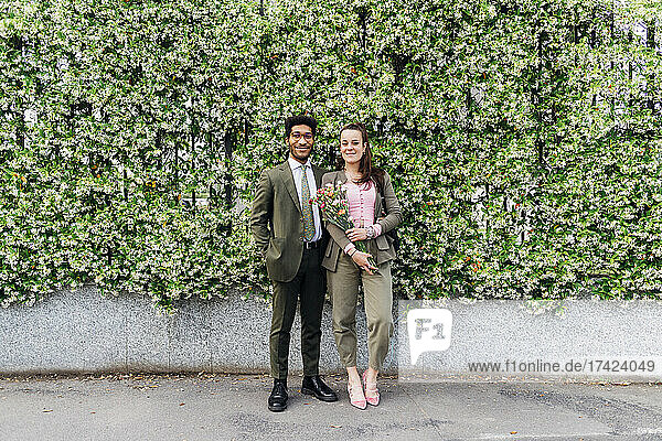 Smiling business couple standing in front of flowering plants