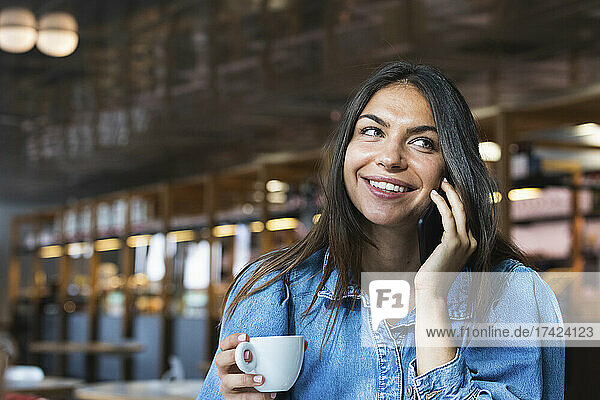 Smiling female freelancer talking on mobile phone at cafe