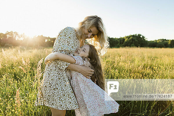 Smiling mother embracing daughter at meadow