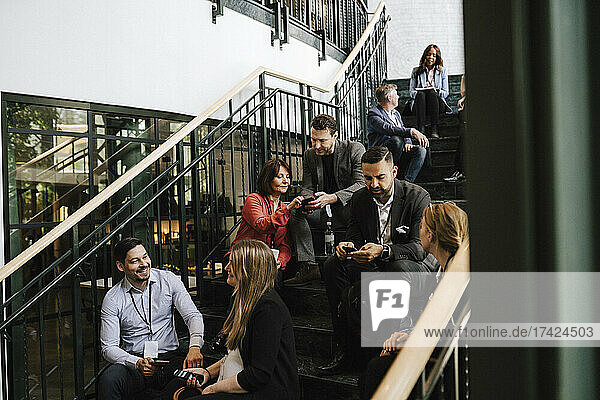 Geschäftsleute und Geschäftsfrauen diskutieren auf einer Treppe sitzend während einer Netzwerkveranstaltung