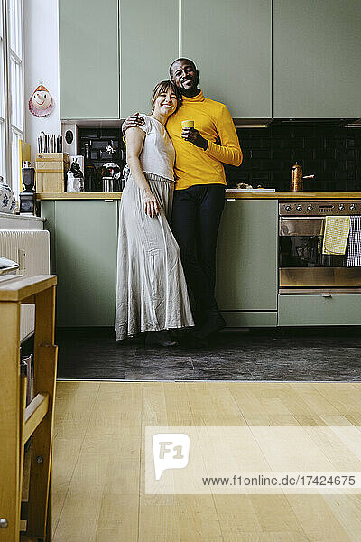 Porträt eines Paares in voller Länge  das zusammen in einer Küche zu Hause steht