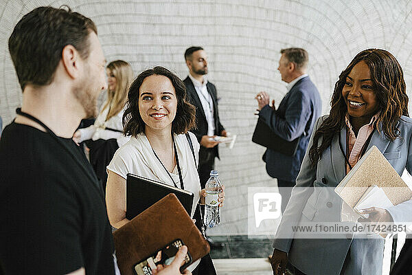 Lächelnde Geschäftsfrauen  die einen männlichen Fachmann bei einer Networking-Veranstaltung beobachten