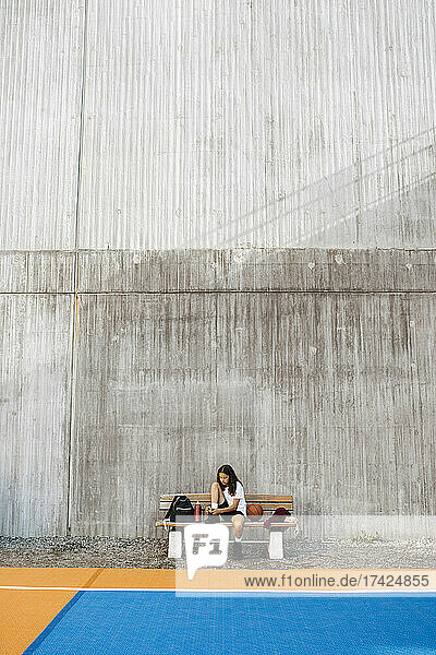 Vorpubertäres Mädchen sitzt auf einer Bank an der Wand