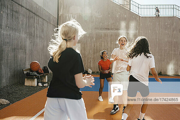 Fröhliche Freundinnen spielen auf dem Basketballplatz