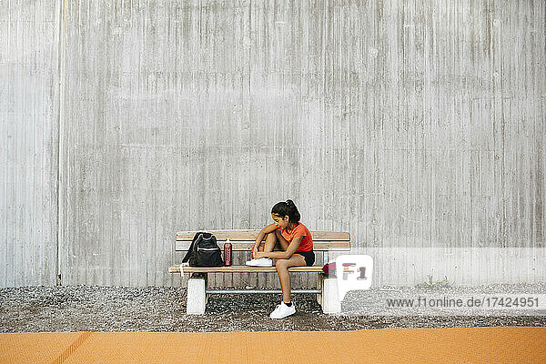 Mädchen bindet Schnürsenkel an der Wand des Sportplatzes