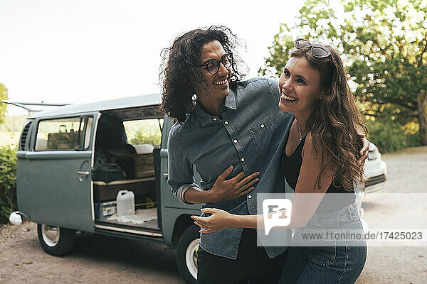 Glückliches junges Paar vor einem Campingwagen stehend