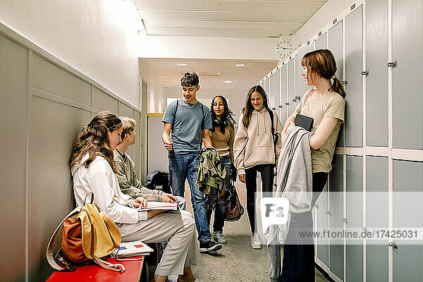 Teenage girls and boys talking in school corridor