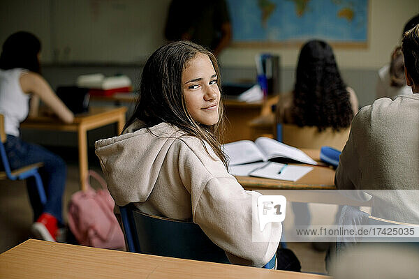 Smiling girl sitting on chair in junior high classroom