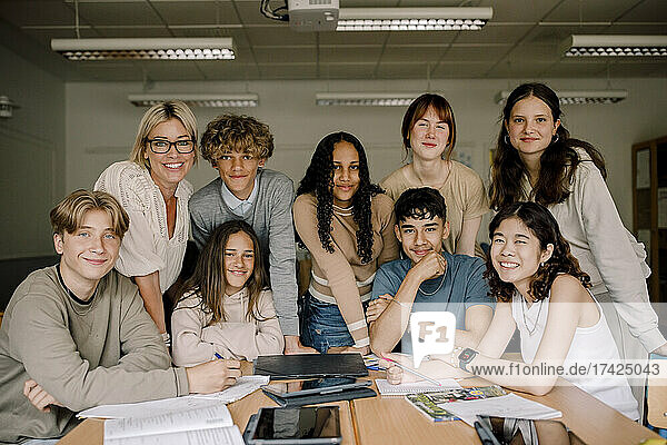 Porträt von lächelnden Teenager-Mädchen und Jungen mit Professorin im Klassenzimmer