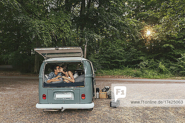 Junges Paar  das sich im Urlaub im Campingbus küsst