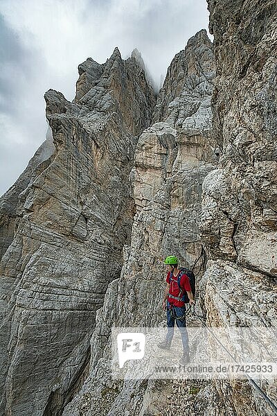 Junger Mann  Wanderer gesichert an einem Stahlseil beim Klettern an einer Felswand  Klettersteig Via Ferrata Francesco Berti  Sorapiss Umrundung  Dolomiten  Belluno  Italien  Europa