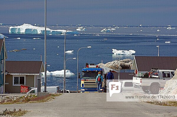 Straßenzug mit Häusern und Nutzfahrzeugen  weite Bucht mit Eisbergen  Ilulissat  Nordamerika  Westgrönland  Grönland  Dänemark  Nordamerika