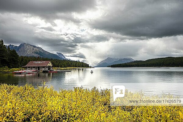 Curly Phillips Boathouse  historic boathouse on the shore of Maligne Lake  behind it mountain range Queen Elizabeth Ranges  autumn vegetation  cloudy sky  Jasper National Park  Rocky Mountains  Alberta  Canada  North America