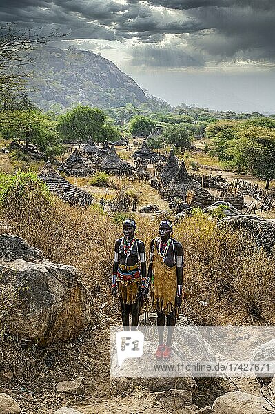 Traditional dressed young girls from the Laarim tribe standing on a rock  Boya hills  Eastern Equatoria  South Sudan  Africa