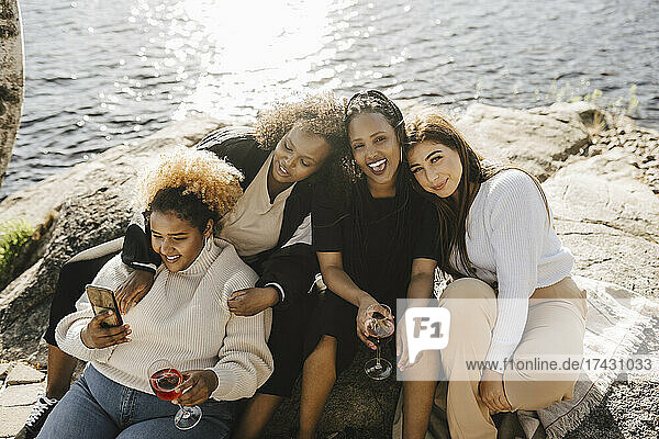 Glückliche Freundinnen sitzen am Seeufer