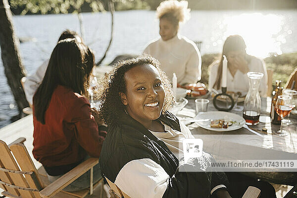Lächelnde Frau mit Freundinnen beim Abendessen im Hinterhof