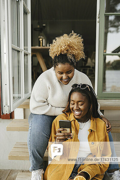 Young woman sharing smart phone with female friend